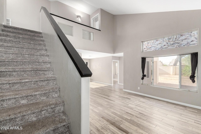 staircase featuring hardwood / wood-style floors and a towering ceiling