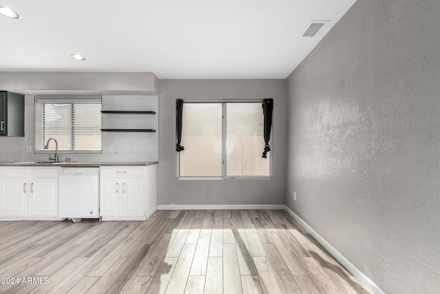 kitchen with backsplash, white dishwasher, white cabinets, sink, and light hardwood / wood-style floors