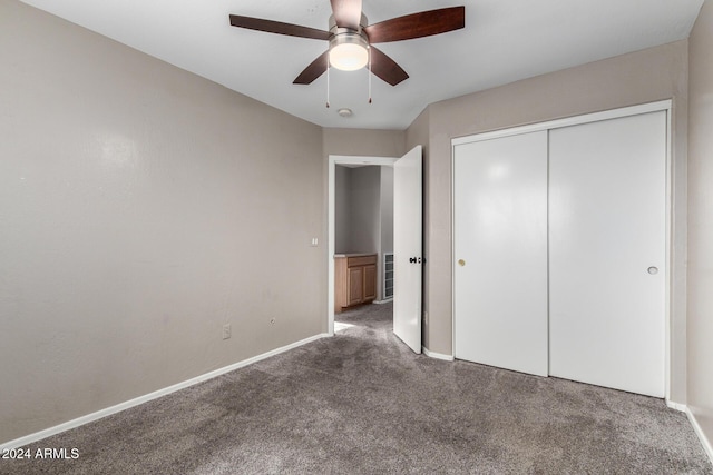 unfurnished bedroom featuring dark colored carpet, a closet, and ceiling fan