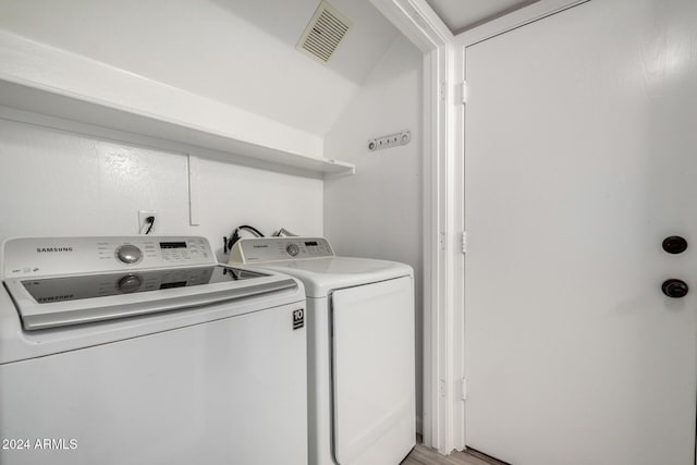 washroom with hardwood / wood-style floors and washing machine and clothes dryer