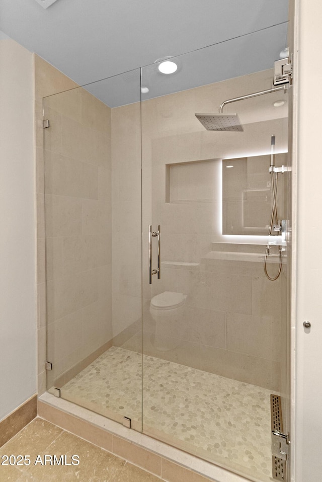 bathroom featuring tile patterned flooring, toilet, and an enclosed shower