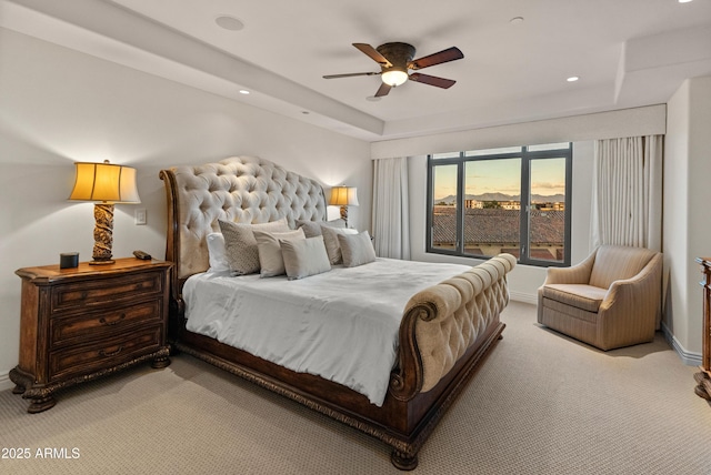 carpeted bedroom featuring ceiling fan and a tray ceiling