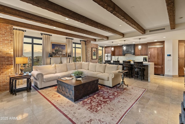 living room featuring beam ceiling and brick wall