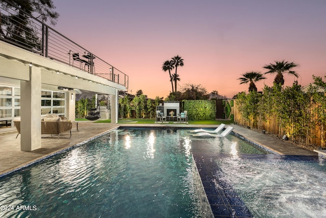 pool at dusk featuring a patio and outdoor lounge area