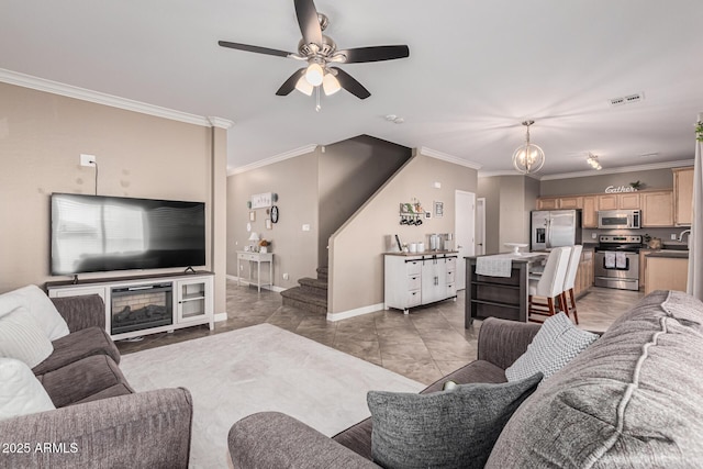 living room featuring ornamental molding, ceiling fan with notable chandelier, and a fireplace