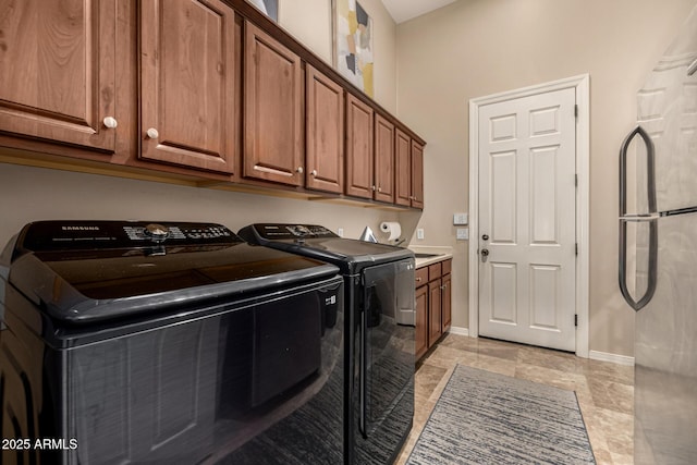 laundry room with washing machine and clothes dryer, cabinet space, and baseboards