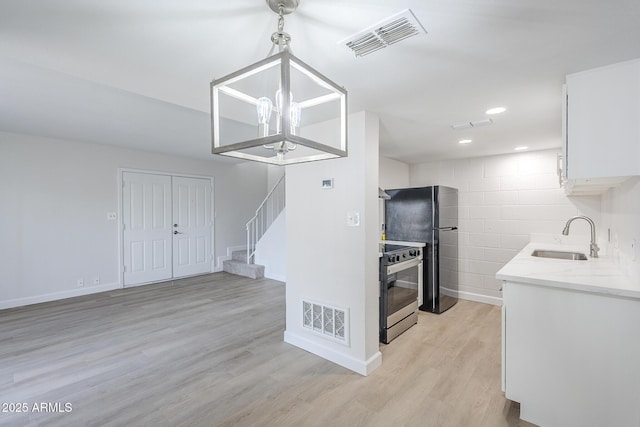 kitchen featuring light wood-style floors, electric range, visible vents, and a sink