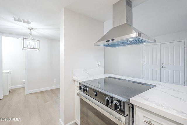 kitchen with stainless steel range with electric cooktop, light stone countertops, wall chimney range hood, and visible vents