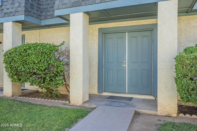 property entrance featuring mansard roof and stucco siding