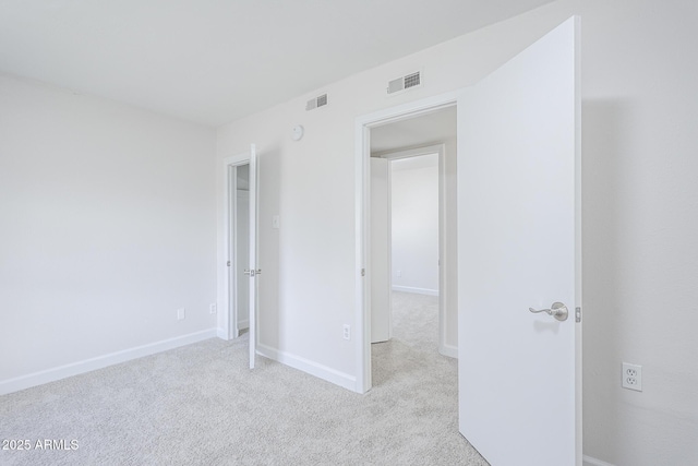 unfurnished bedroom with baseboards, visible vents, and light colored carpet