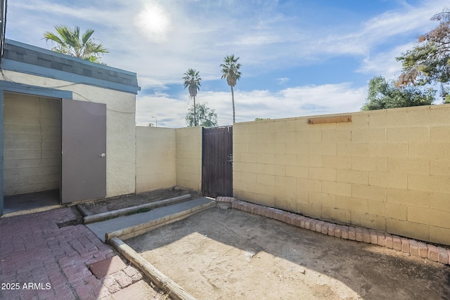 view of gate with fence and a patio