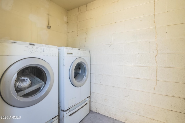 washroom featuring concrete block wall, washing machine and dryer, and laundry area