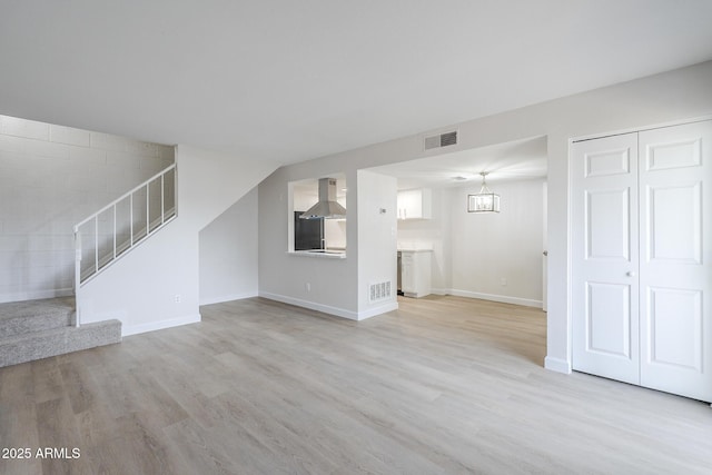 unfurnished living room with stairway, visible vents, and light wood-type flooring