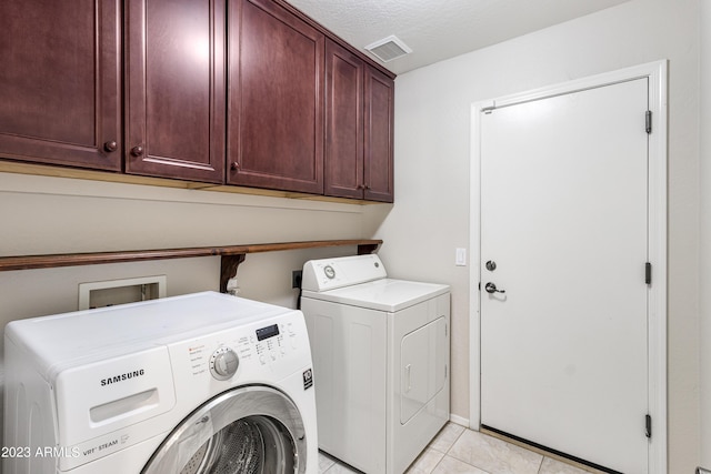 laundry area with cabinets, a textured ceiling, light tile patterned floors, and washing machine and dryer