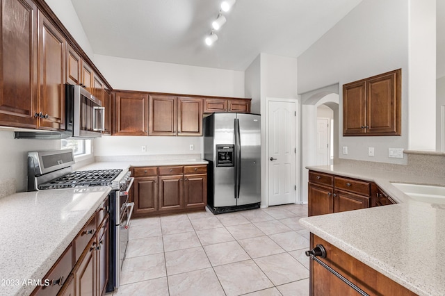 kitchen with light stone counters, light tile patterned floors, appliances with stainless steel finishes, and sink