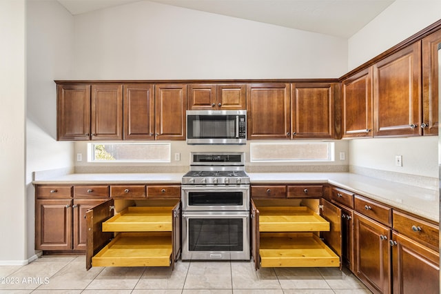 kitchen featuring light tile patterned floors, appliances with stainless steel finishes, and lofted ceiling