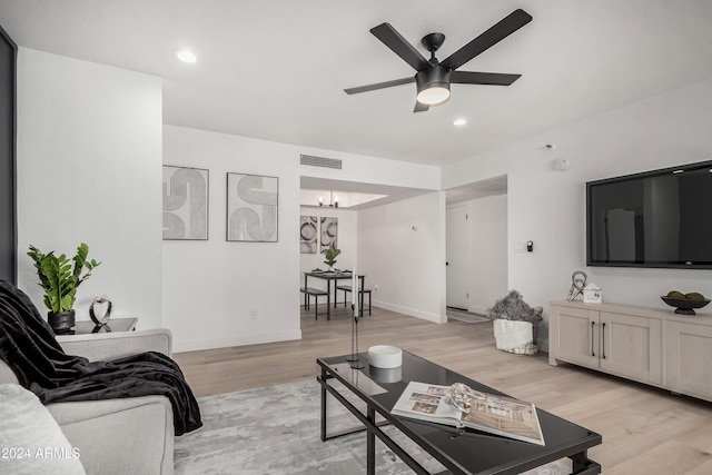 living room with ceiling fan with notable chandelier and light wood-type flooring