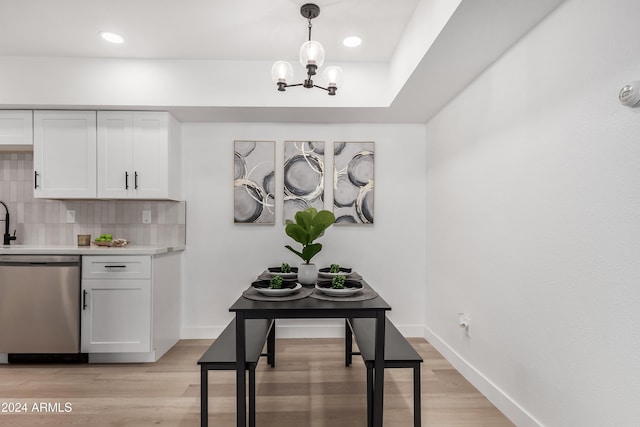 kitchen featuring dishwasher, hanging light fixtures, tasteful backsplash, light hardwood / wood-style floors, and white cabinets