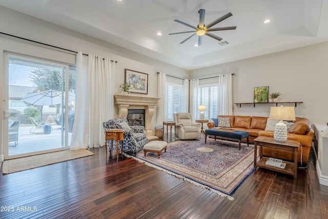 living room with a tray ceiling, ceiling fan, and wood-type flooring