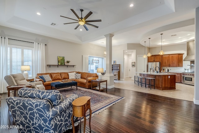 living room featuring dark hardwood / wood-style floors, a raised ceiling, and ceiling fan