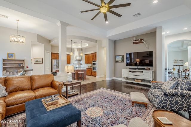 living room with dark hardwood / wood-style flooring and ceiling fan with notable chandelier