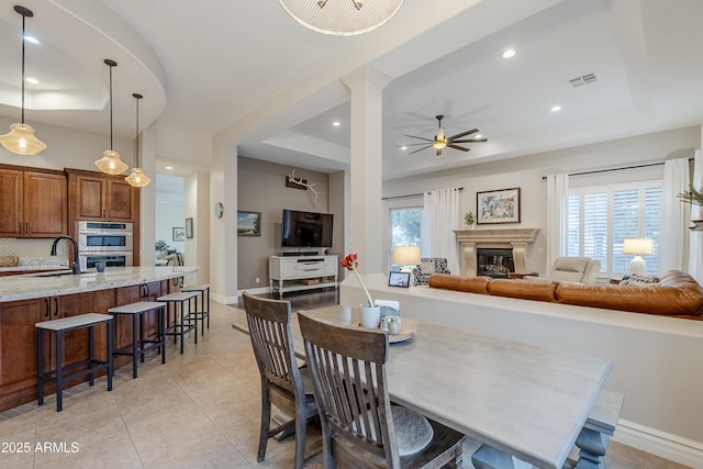 tiled dining room with a wealth of natural light, a tray ceiling, ceiling fan, and sink