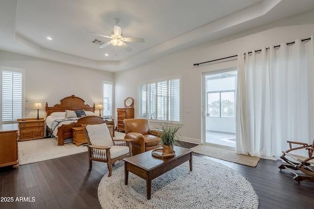 bedroom with dark hardwood / wood-style flooring, a tray ceiling, and ceiling fan