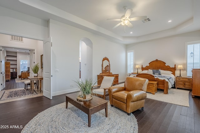 bedroom featuring dark hardwood / wood-style flooring, a tray ceiling, and ceiling fan