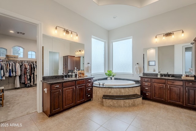 bathroom featuring tiled bath, tile patterned flooring, and vanity