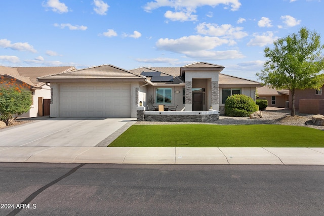 prairie-style home with a garage, a front yard, and solar panels