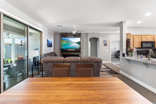 living room with sink, dark colored carpet, and ceiling fan