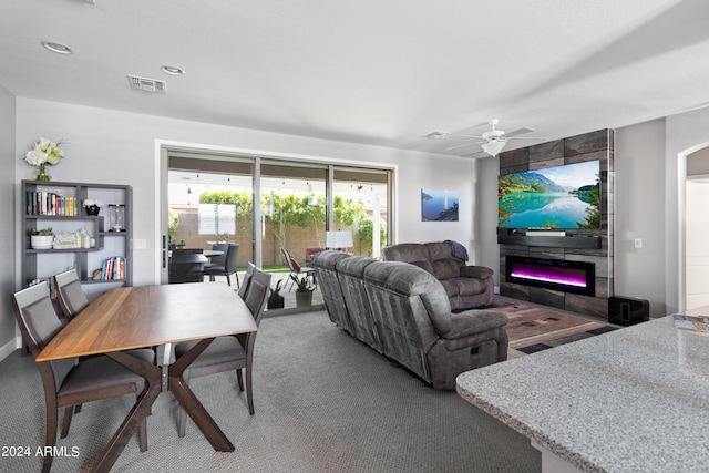 living room featuring ceiling fan, carpet, and a tile fireplace