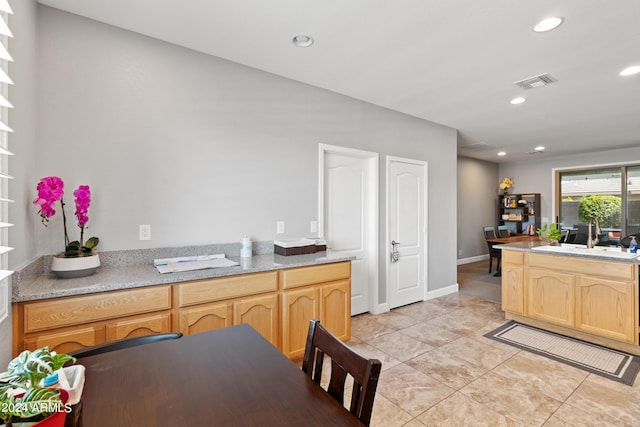 kitchen featuring sink, light tile patterned flooring, light brown cabinetry, and light stone counters