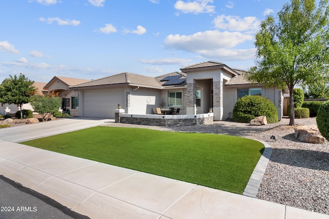 view of front of property featuring a garage, a front yard, and solar panels