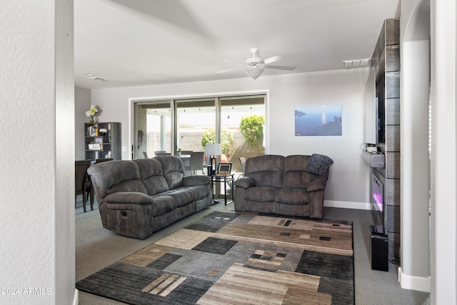 living room featuring ceiling fan and dark carpet