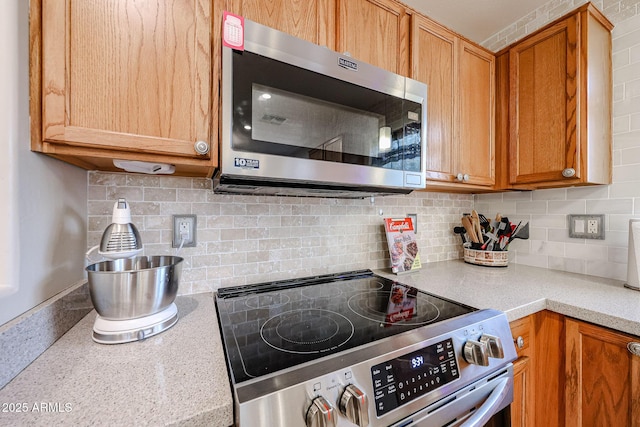 kitchen with stainless steel appliances, brown cabinets, tasteful backsplash, and light countertops