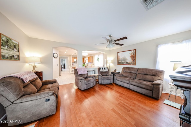 living area with visible vents, arched walkways, and light wood-style floors