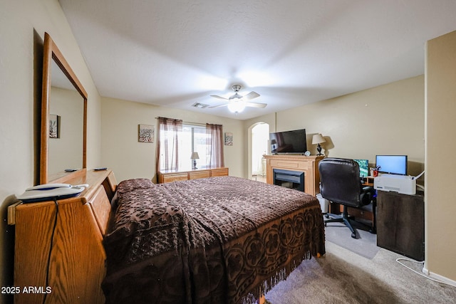 carpeted bedroom with visible vents, a fireplace, and a ceiling fan