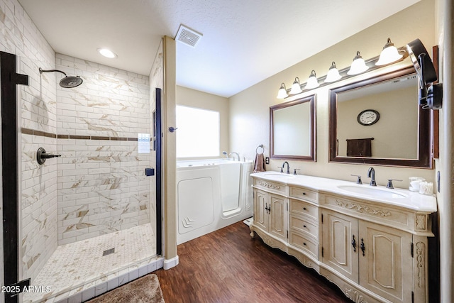 full bath featuring a sink, visible vents, wood finished floors, and washing machine and dryer