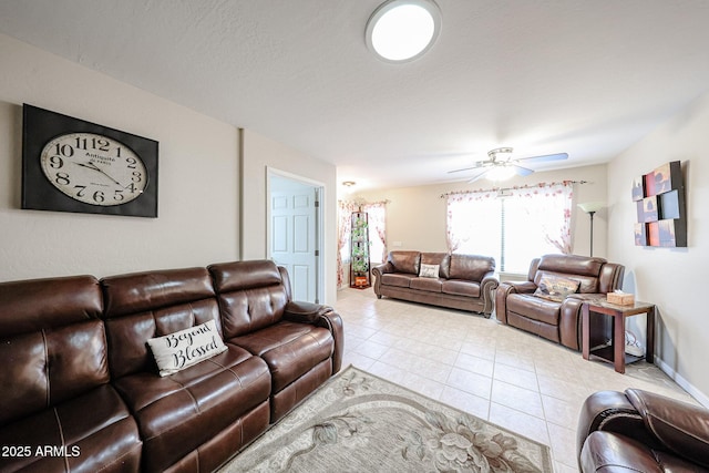 living area featuring a textured ceiling, tile patterned floors, baseboards, and ceiling fan