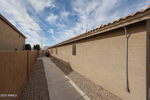 view of side of property with fence and stucco siding