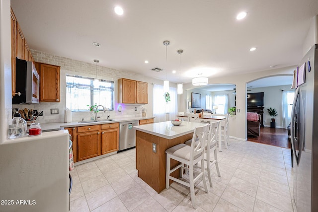 kitchen featuring visible vents, a breakfast bar, arched walkways, stainless steel appliances, and a sink