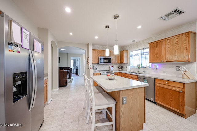 kitchen featuring visible vents, a sink, backsplash, stainless steel appliances, and arched walkways