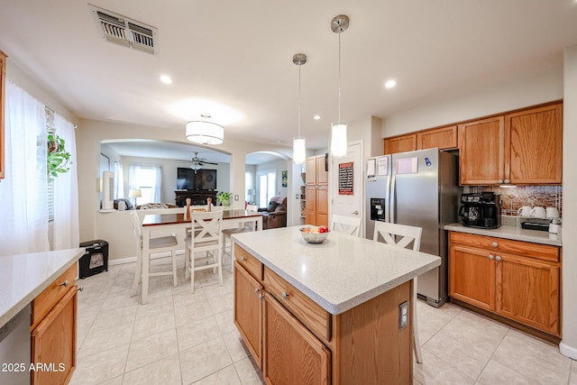 kitchen featuring visible vents, arched walkways, stainless steel appliances, decorative backsplash, and light countertops