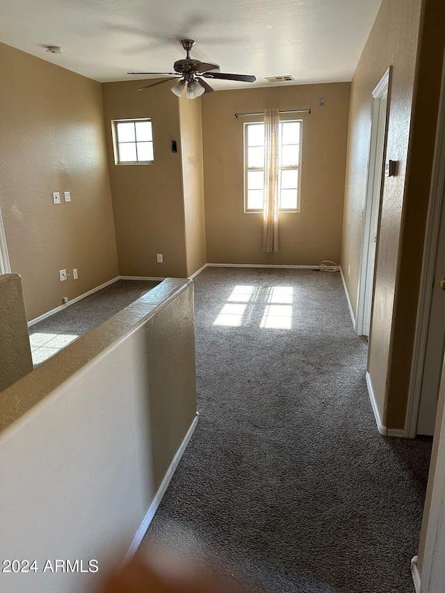 unfurnished room with ceiling fan, light carpet, and a wealth of natural light