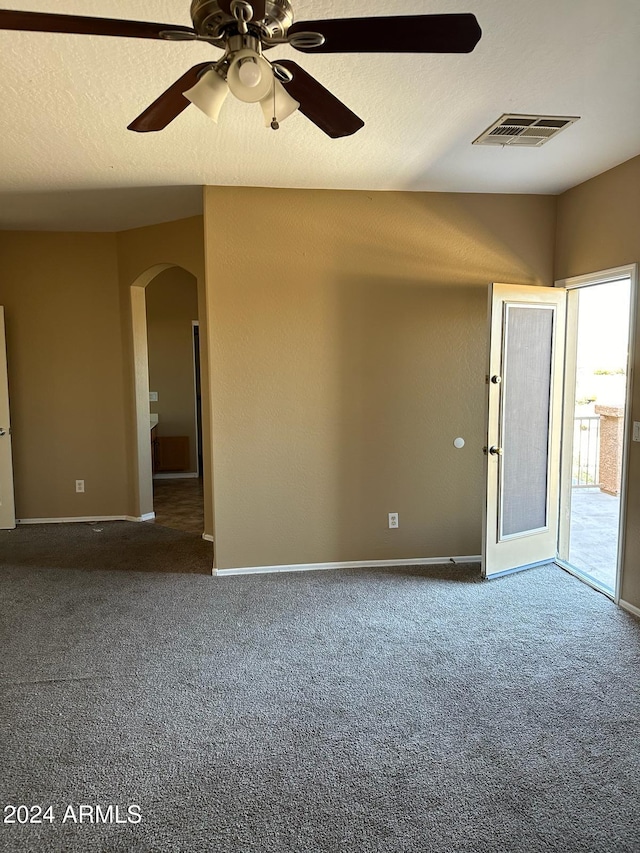 spare room with dark colored carpet, a textured ceiling, and ceiling fan