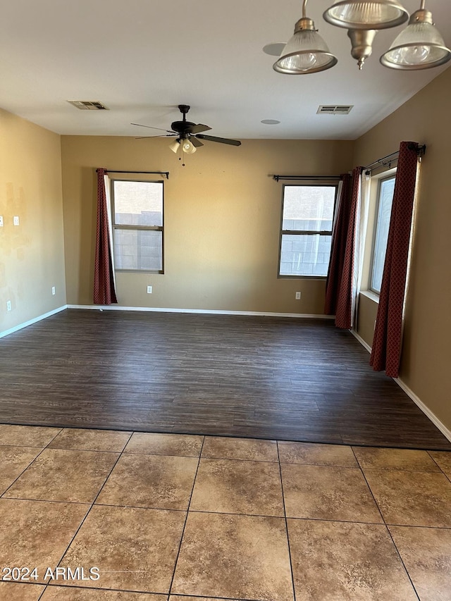 unfurnished room featuring ceiling fan, a healthy amount of sunlight, and dark hardwood / wood-style flooring