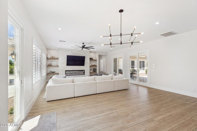 3356 E Vallejo Ct, Gilbert, AZ 85298 - living room featuring a tiled fireplace, recessed lighting, light wood-style flooring, ceiling fan with notable chandelier, and visible vents