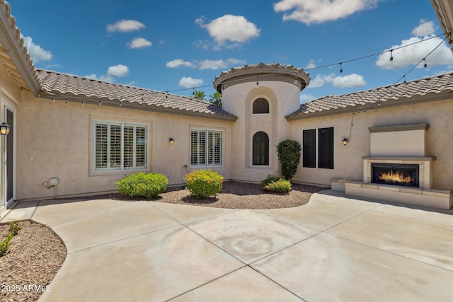 3356 E Vallejo Ct, Gilbert, AZ 85298 - exterior space featuring stucco siding, a patio area, a lit fireplace, and a tile roof
