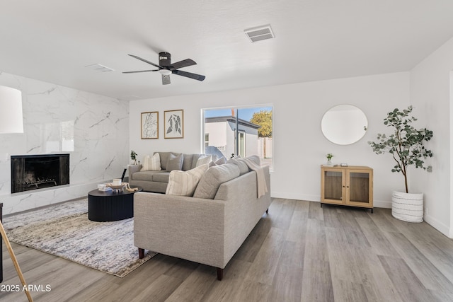 living room with ceiling fan, hardwood / wood-style floors, and a fireplace